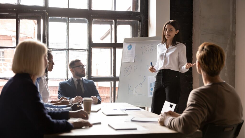 Équipe PME en pleine réflexion sur une stratégie marketing avec schéma au tableau